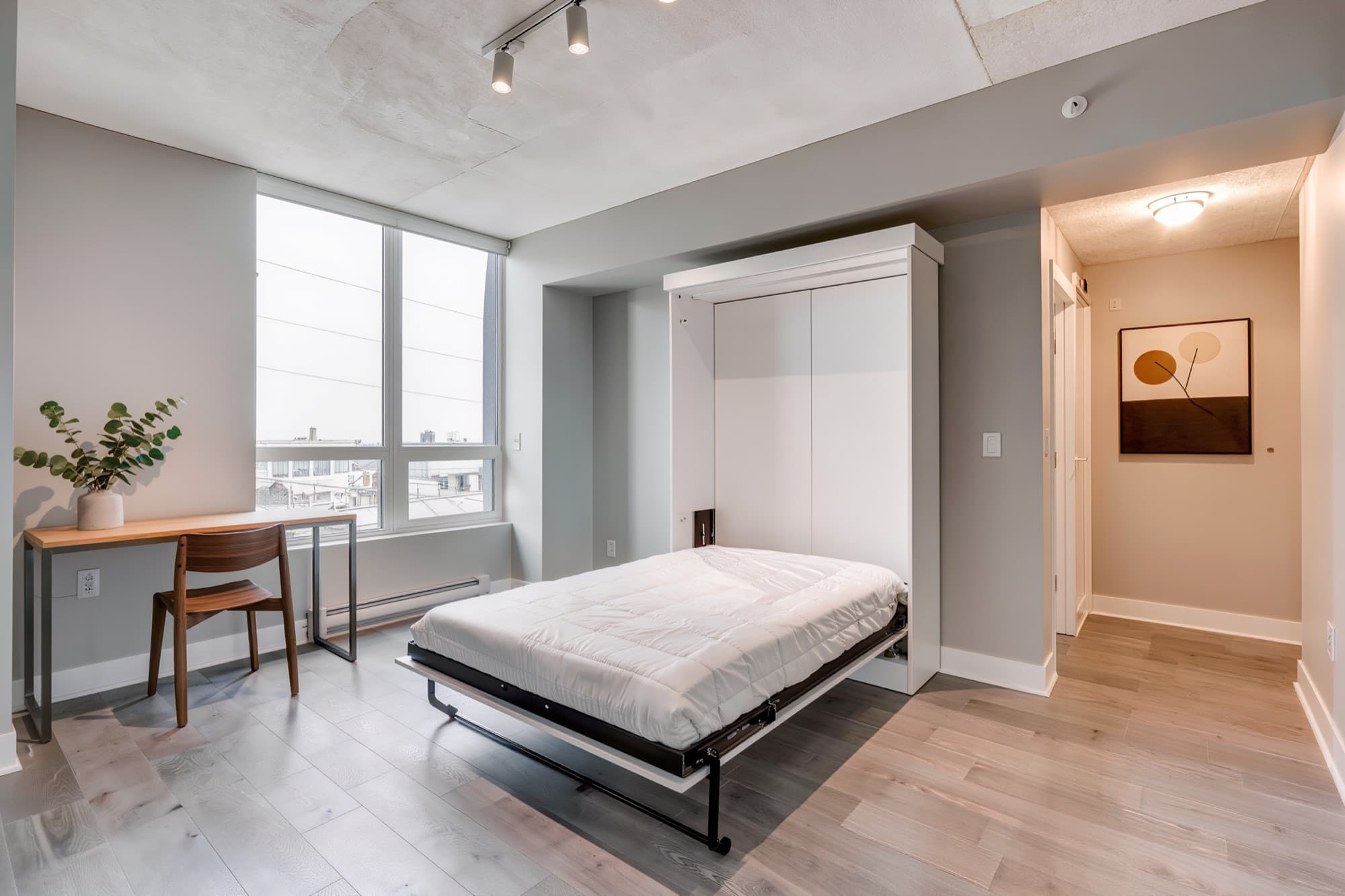 White full size murphy bed folded down in a bright condo studio